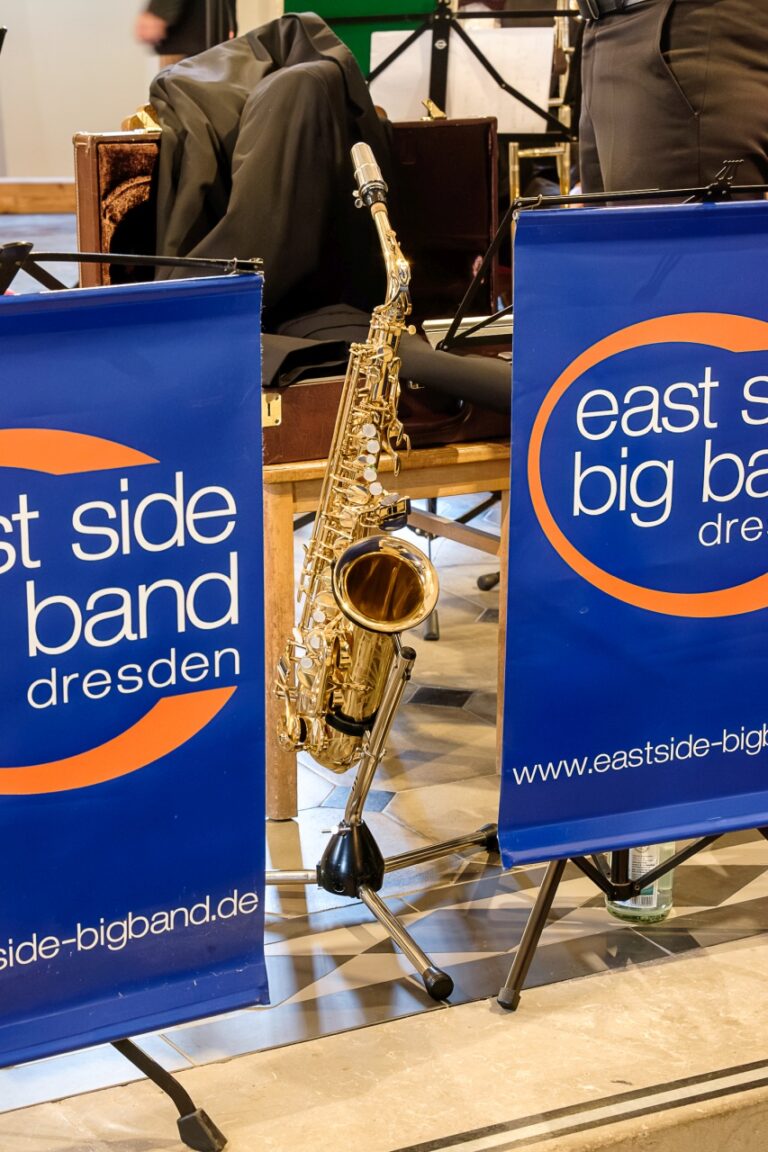 Detailaufnahme: ein Saxophon steht zwischen zwei Logo-Bannern.